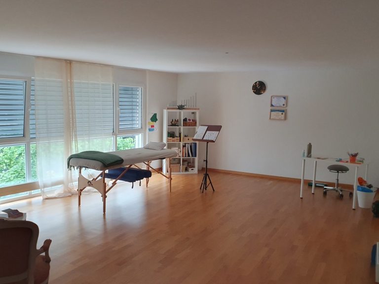 Blick von Oben in den Raum hinein. Die Liege, einen Stuhl, kleiner Tisch und einen Teil des Bücherregals ist zu sehen.